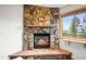 A cozy corner fireplace with natural stone surround and hearth and a window at 29825 Kennedy Gulch Rd, Conifer, CO 80433