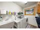 Functional laundry room with modern washer and dryer, utility sink, storage shelf and natural light from window at 29825 Kennedy Gulch Rd, Conifer, CO 80433