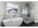 Bright bathroom featuring a modern tub, marble tile, and glass-enclosed shower with dual showerheads at 11722 W Belmont Pl, Littleton, CO 80127