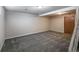 A finished basement space features neutral paint and carpet, with a door to the right and stairs to the right at 1791 Quail St, Lakewood, CO 80215