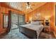 Comfortable bedroom featuring wood walls, a ceiling fan, and an outside deck access at 34788 Forest Estates Rd, Evergreen, CO 80439
