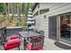 A wooden deck features a dining set with red cushions, an umbrella, and a hot tub against a backdrop of trees at 34788 Forest Estates Rd, Evergreen, CO 80439
