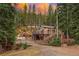 Charming mountain home with wrap-around deck nestled among tall evergreen trees at sunset at 34788 Forest Estates Rd, Evergreen, CO 80439