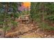 Mountain home exterior with deck, surrounded by mature trees and a natural stream at 34788 Forest Estates Rd, Evergreen, CO 80439