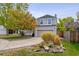 Beautiful landscaping surrounds a two-story house with a gray exterior and a spacious driveway leading to an attached garage at 8510 Union Cir, Arvada, CO 80005