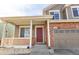 Inviting front porch leads to a classic two-story house with brick accents and a two-car garage at 9703 Ogden Ct, Thornton, CO 80229