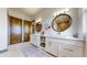 Elegant bathroom with double vanities, round mirrors, white cabinets, and wood paneled doors at 11194 W Yucca, Littleton, CO 80125