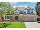 Charming two-story home featuring a brick facade, lush lawn, mature landscaping, and attached two car garage at 10068 Granite Hill Dr, Parker, CO 80134