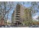 Brick high-rise building with balconies and mature trees in a landscaped setting at 1150 Vine St # 1006, Denver, CO 80206