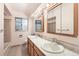 Bathroom featuring dual sinks, wood cabinets, and a large mirror with vanity lighting at 502 Nile St, Aurora, CO 80010