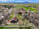 Aerial view of a home and barn with views of the golf course and mountains in the distance at 11489 W Bear Creek Dr, Lakewood, CO 80227