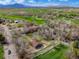 Expansive aerial view showcasing a sprawling home near a lush golf course and scenic mountain backdrop at 11489 W Bear Creek Dr, Lakewood, CO 80227