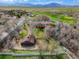 Aerial view of a home and barn with views of the golf course and mountains in the distance at 11489 W Bear Creek Dr, Lakewood, CO 80227
