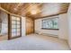 Cozy bedroom featuring carpeted floors, a wood-paneled ceiling, closet, and natural light from a window at 11489 W Bear Creek Dr, Lakewood, CO 80227