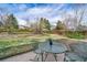 Relax on the patio within the serene backyard featuring lush lawn, mature trees, and a charming sitting area at 18263 E Berry Dr, Centennial, CO 80015