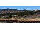 A property view with rolling hills, mature trees and vegetation, and a chain-link fence in the foreground at 785 Century Ln, Monument, CO 80132