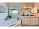 Bright bathroom featuring double vanity with marble countertop, soaking tub, and scenic backyard views at 960 Promontory Cir, Elizabeth, CO 80107