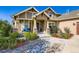 Inviting front entrance featuring stone accents, a blue bench, and lush landscaping at 960 Promontory Cir, Elizabeth, CO 80107