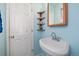 Charming bathroom with a pedestal sink, wooden shelving, light blue walls, and tiled flooring at 11173 Emerald Ln, Conifer, CO 80433