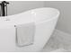 Close-up of a luxurious freestanding tub with a modern faucet and a soft towel, set on elegant marble flooring at 61800 E 32Nd Ct, Strasburg, CO 80136