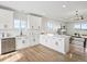 Open-concept kitchen with white cabinets, hardwood floors, and connecting views to the living room at 61800 E 32Nd Ct, Strasburg, CO 80136