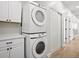 Bright laundry area features stacked washer and dryer units, and plenty of cabinet storage at 61800 E 32Nd Ct, Strasburg, CO 80136