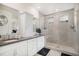 Bright bathroom featuring double sinks, white cabinets, a mirror, and a glass-enclosed shower at 8815 S Tibet Ct, Aurora, CO 80016