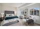 Bright bedroom featuring a plush bed with a tufted headboard, sitting area, and natural light from windows at 8815 S Tibet Ct, Aurora, CO 80016