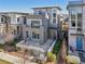 Modern two-story home features gray siding, stone accents, metal railings, and an expansive front porch at 9006 E 60Th Ave, Denver, CO 80238