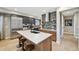 Modern kitchen with a large island, stainless steel appliances, dark cabinets, and stylish backsplash and floating shelves at 9006 E 60Th Ave, Denver, CO 80238