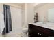 This bathroom features a shower/tub combo, tile flooring, and dark wooden cabinets with chrome knobs at 15205 W Iliff Ave, Lakewood, CO 80228