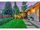 Landscaped backyard featuring green grass, stepping stones, and manicured plants at 13 Pinyon Pine Rd, Littleton, CO 80127