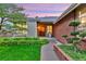 Charming front entrance with a wooden door, brick accents, and lush landscaping at 13 Pinyon Pine Rd, Littleton, CO 80127