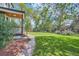 Lush backyard with a green lawn, mature trees, stone walkway, and porch with black railing at 5127 Lowell Blvd, Denver, CO 80221