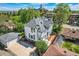 Aerial view of white home with gray roof, detached garage, driveway, landscaping, and nearby school at 5127 Lowell Blvd, Denver, CO 80221
