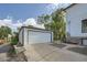 Detached two-car garage with white door, concrete driveway, and brick accents near the house at 5127 Lowell Blvd, Denver, CO 80221