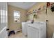Bright laundry room features a side-by-side washer and dryer, and practical shelving for storage with window at 7763 S Elk St, Aurora, CO 80016
