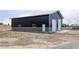 Exterior view of a large barn with two garage doors, light-colored trim and dark metal siding at 5917 Black Forest Dr, Elizabeth, CO 80107