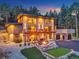 Striking multi-story home boasts a well-lit stone facade, balcony, fire pit, and putting green against a backdrop of lush trees at 7793 Elk Path Way, Morrison, CO 80465
