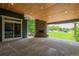 Spacious outdoor patio with stone fireplace, wood ceiling, and access to large yard at 7126 E 162Nd Ct, Brighton, CO 80602