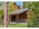 Exterior view of rustic wood cabin with covered carport and natural stone accents surrounded by trees at 1152 Ski Hill Rd, Breckenridge, CO 80424