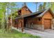 Rustic wood cabin featuring a covered carport, garage, stone accents and lush surrounding landscape at 1152 Ski Hill Rd, Breckenridge, CO 80424