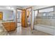 Bright bathroom with dual sinks, wooden cabinets, and shower-tub combo with glass door at 132 Loveland Way, Golden, CO 80401