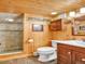 Bathroom featuring a tiled shower, toilet, vanity, wood-paneled wall and ceiling at 1000 Lodgepole Dr, Evergreen, CO 80439