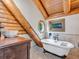 Charming bathroom boasts a clawfoot tub, wood beams, and unique octagon-shaped window at 1000 Lodgepole Dr, Evergreen, CO 80439
