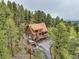 Elevated aerial view showcasing the log home's exterior, landscaping, surrounding trees, and driveway at 1000 Lodgepole Dr, Evergreen, CO 80439