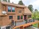 Charming log home featuring a spacious deck with black metal railings and a stone foundation, nestled in a wooded area at 1000 Lodgepole Dr, Evergreen, CO 80439
