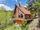 Log home featuring a stone chimney and a large window overlooking a lush forest landscape, with an inviting outdoor deck at 1000 Lodgepole Dr, Evergreen, CO 80439