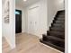 Bright entryway featuring light wood floors, a dark front door, and a staircase at 6501 Welch Ct, Arvada, CO 80004