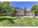View of the backyard featuring a grill, wooden fence, concrete patio, grass and trees at 1584 S Fraser Way, Aurora, CO 80012